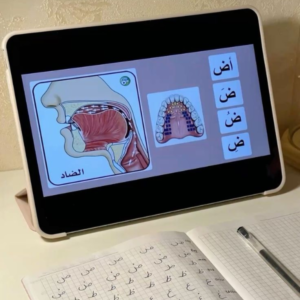 "Tablet displaying a Makharij lesson showing the correct pronunciation of the Arabic letter Dad (ض) with tongue placement diagrams and an Arabic writing practice notebook."